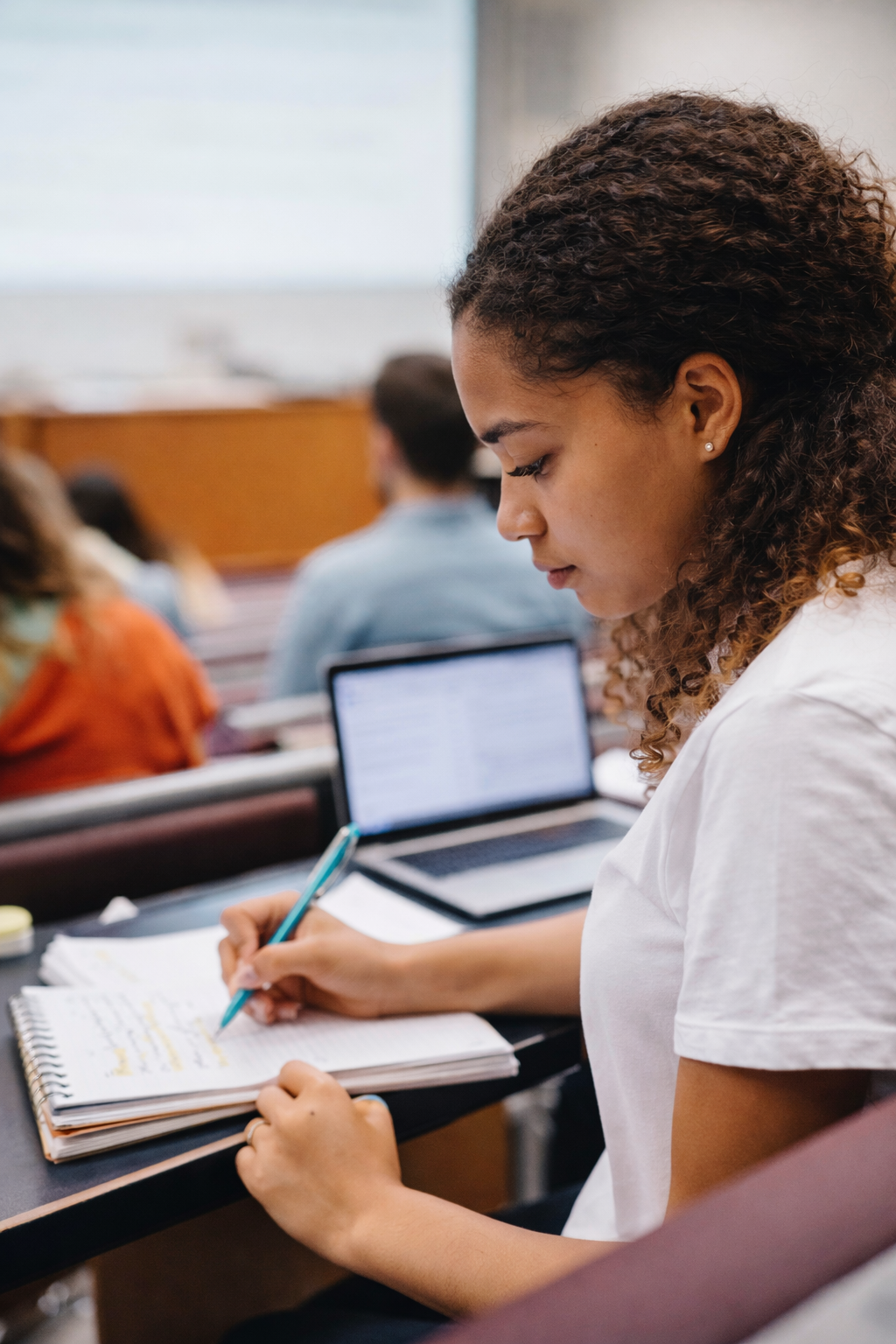 College student taking notes during a lecture, using a structured checklist-style approach.